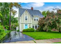 Charming Tudor-style home with a manicured lawn, mature trees, and a vibrant blue front door at 329 W Hampton Dr, Indianapolis, IN 46208