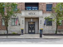 Inviting building entrance with stone facade, flags, and manicured landscaping enhances the curb appeal at 355 E Ohio St # 314, Indianapolis, IN 46204