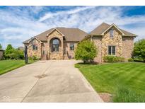 Beautiful brick and stone home with a basketball court and a manicured lawn on a sunny day at 4890 Benthaven E Dr, Bargersville, IN 46106