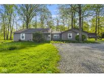 Charming single-story home with a gravel driveway and mature trees providing ample shade at 5039 Five Points Rd, Indianapolis, IN 46239