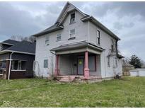 Two story home with covered porch, showing peeling paint and overgrown yard at 1014 W 33Rd St, Indianapolis, IN 46208