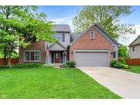 Charming two-story home featuring a well-manicured lawn, brick accents, and an attached two car garage at 10310 Foxwood W Dr, Carmel, IN 46280