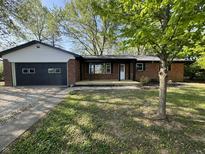 Charming brick ranch-style home with an attached garage and a cozy front porch, all surrounded by mature trees at 1725 E 100 S, Lebanon, IN 46052