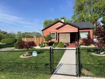 Charming single-story home featuring a well-manicured lawn, secure black fencing, and lovely landscaped garden at 3302 N Gladstone Ave, Indianapolis, IN 46218