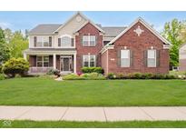 Charming two-story brick home featuring a welcoming front porch and lush green lawn at 3743 Earhart Dr, Carmel, IN 46074