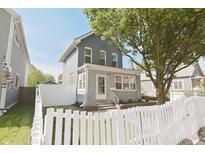 Charming two-story home featuring a brick foundation, inviting front porch, and a lovely white picket fence at 701 Lincoln St, Indianapolis, IN 46203