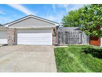 Attached two-car garage featuring a white door and brick siding, complemented by a well-kept lawn at 7642 Lancer Ln, Lawrence, IN 46226