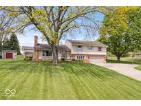 Charming two-story home with landscaped yard and mature trees on a sunny day at 1242 W Huntsville Rd, Pendleton, IN 46064