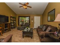 Cozy living room with brown sofa, coffee table, ceiling fan, and large front window at 270 Rapid Rill Ln, Brownsburg, IN 46112