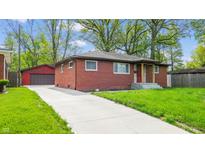 Charming brick home with a well-manicured lawn and a long driveway leading to a detached garage at 4213 N Audubon Rd, Indianapolis, IN 46226