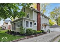 Charming two-story home with a red brick chimney, screened-in porch, lush yard, and detached two-car garage at 4447 N College Ave, Indianapolis, IN 46205