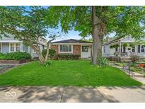 Charming brick home featuring a well-maintained lawn and mature trees in a quiet neighborhood at 4956 W 11Th St, Speedway, IN 46224