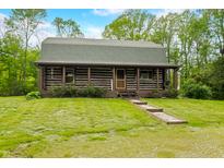 Charming log cabin featuring a cozy front porch, stone walkway, and well-maintained lawn with mature trees in a serene setting at 6968 S 300 W, Trafalgar, IN 46181