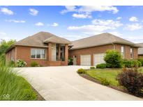 Inviting brick home featuring an attached two car garage and winding concrete driveway under a partly cloudy sky at 888 Westcreek Dr, Columbus, IN 47201