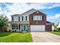 Charming two-story home boasts a well-manicured lawn and an inviting, covered front porch with vibrant flower accents at 1257 Rosemary Ct, Greenfield, IN 46140