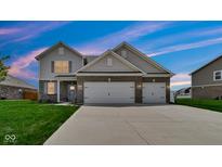 Two-story home featuring a two-car garage, neutral siding, brick accents and well-maintained lawn at 4763 W Tradwell Dr, New Palestine, IN 46163