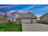Charming two-story home featuring a well-manicured lawn, brick accents, and an attached two-car garage at 4763 W Tradwell Dr, New Palestine, IN 46163