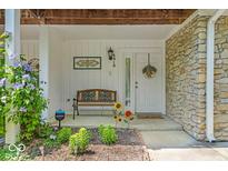 Inviting front porch with stone accents, bench seating, and charming floral decor, offering a warm welcome at 6916 Ralph Ct, Indianapolis, IN 46220