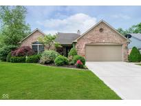 Charming brick home with lush landscaping, green lawn, and an attached two-car garage at 10833 Tournament Ln, Indianapolis, IN 46229