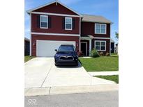 Two-story red house featuring an attached garage, well-maintained lawn, and a long driveway at 11204 Sashing Way, Monrovia, IN 46157