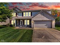 Two-story home featuring a brick facade, attached two-car garage, and a well-manicured front lawn under a dramatic sunset sky at 1238 Aggie Ln, Indianapolis, IN 46260