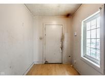 A view of the entryway, with a door, a window, and peeling paint on the walls at 2114 Sugar Grove Ave, Indianapolis, IN 46202