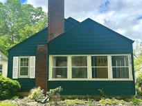 Charming home with a brick chimney, a yellow front door, and meticulously landscaped front yard at 310 S Butler Ave, Indianapolis, IN 46219