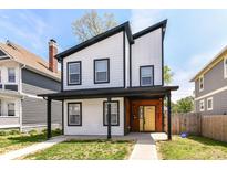 Modern two-story home features a striking black-and-white color scheme with a welcoming yellow door at 3241 Ruckle St, Indianapolis, IN 46205