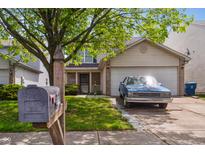 Traditional two-story home featuring a well-maintained lawn, mature trees and a blue car parked in the driveway at 3937 Candle Berry Dr, Indianapolis, IN 46235