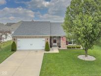 Charming brick home featuring a two-car garage, a well-manicured lawn, and mature trees at 4309 Viva Ln, Indianapolis, IN 46239