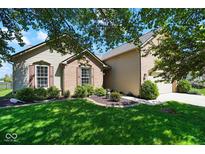 Charming home featuring a well-manicured front yard with lush green grass and beautiful landscaping at 5047 Skipping Stone Dr, Indianapolis, IN 46237