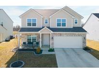 Charming two-story home with a brick and beige exterior, featuring a well-manicured lawn and attached two-car garage at 6903 Aster Dr, Pendleton, IN 46064