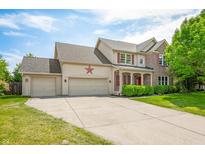 Charming two-story home featuring a three-car garage, red accents, and a well-maintained front lawn at 7023 Hartington Pl, Indianapolis, IN 46259
