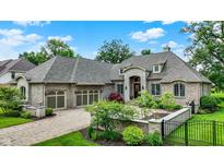 Stunning brick home featuring a stone entryway, lush landscaping, and an attached three-car garage at 8905 Stonebriar Dr, Indianapolis, IN 46259