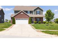Two-story home featuring green siding, brick accents, an attached two car garage and a well-manicured front yard at 928 Cherry Tree Ln, Greenwood, IN 46143