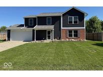 Two story home boasts dark siding, brick accents, a well manicured lawn, and an attached two car garage at 1214 Lindsey Ln, Lebanon, IN 46052