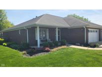 Charming brick home featuring a manicured lawn, inviting porch, and attached garage at 123 Old Farm Rd, Danville, IN 46122