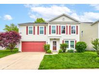 Charming two-story home with a red door, red garage door and red shutters with landscaped front yard and a beautiful tree at 13295 Patriotic Way, Fishers, IN 46037