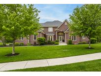 Beautiful brick home featuring a well-manicured lawn, mature trees, and inviting front entrance at 13309 Carmichael Ln, Carmel, IN 46074