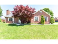 Charming brick home featuring a lush front lawn, mature trees, and meticulously maintained landscaping at 3126 Oakmont Dr, Lapel, IN 46051