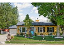 Charming yellow home with beautifully landscaped front yard, blue door, and detached garage at 3433 Brewer Dr, Indianapolis, IN 46222