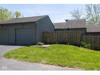 Attached garage and front yard featuring green grass and wooden fence at 5077 Vantage Point Rd # 1 Wm-5-1, Avon, IN 46123