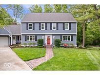 Charming two-story home featuring a brick walkway, landscaped yard, and a pop of color from the red front door at 5958 Cape Cod Ct, Indianapolis, IN 46250