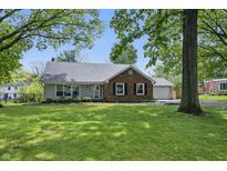 Charming one-story home with a brick facade, well-maintained lawn, and beautiful mature trees at 6839 Chaucer Ct, Indianapolis, IN 46220