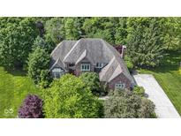Stunning aerial view of a brick home surrounded by lush greenery and mature trees at 7372 Fox Hollow Rdg, Zionsville, IN 46077