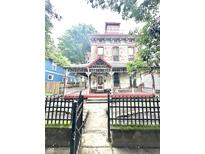 Charming multi-story home featuring a welcoming front porch and a decorative fence at 866 Fletcher Ave, Indianapolis, IN 46203