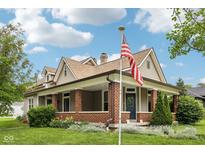 Charming two-story home with a brick-columned front porch and an American flag in a lush, landscaped yard at 910 E Pike St, Martinsville, IN 46151
