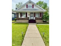 Charming home with a well-maintained lawn, walkway, and a welcoming front porch at 106 S Denny St, Indianapolis, IN 46201