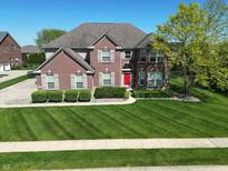 Beautiful two-story brick home boasts a lush lawn, vibrant landscaping, and a striking red front door at 2219 Stone Manor Ct, Avon, IN 46123