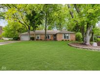 Charming red brick ranch home featuring a spacious green lawn and mature trees at 3698 E 106Th St, Carmel, IN 46033